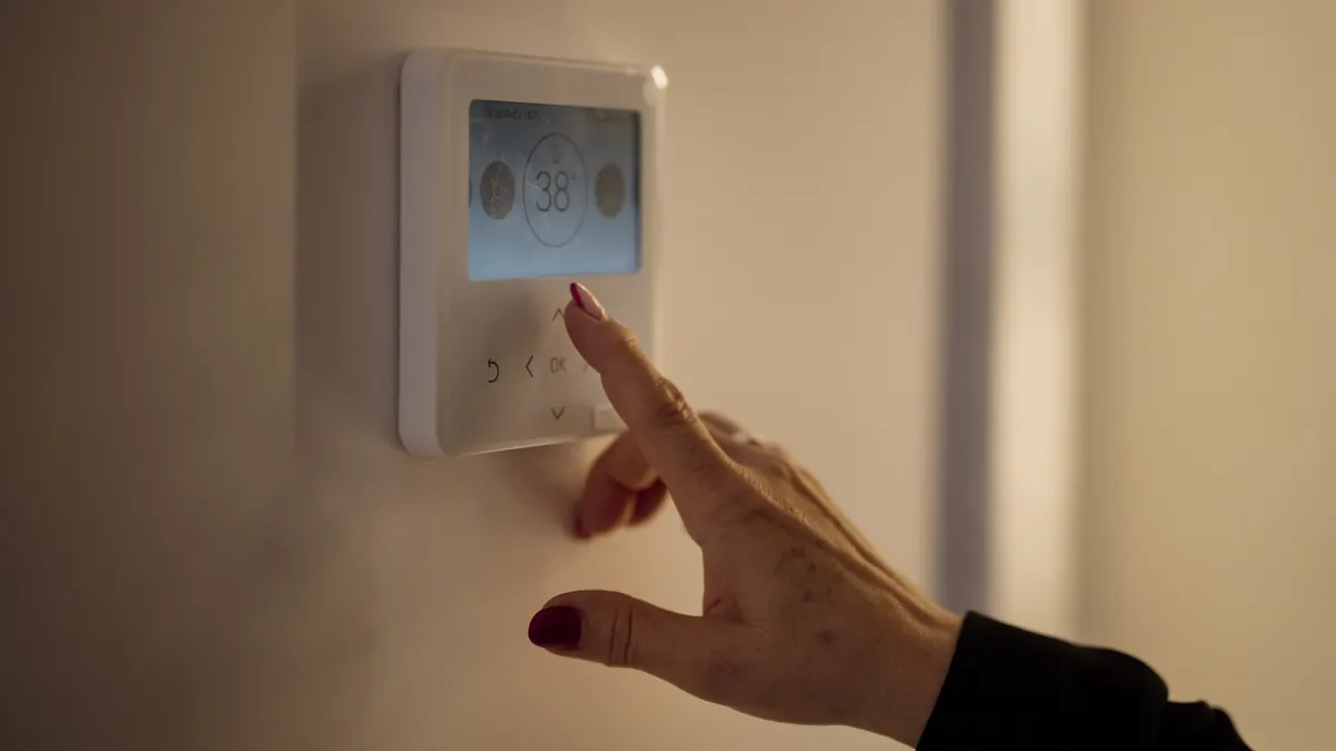 Persona ajustando la programación de un termostato digital de pared en casa