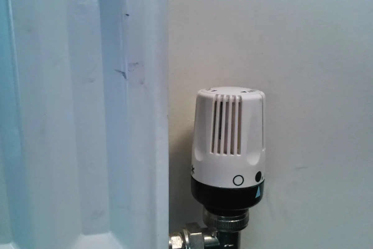 Válvula termostática de un radiador de agua caliente instalada junto a la pared